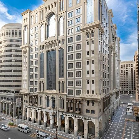 Al Aqeeq Madinah Hotel Медина Экстерьер фото The photo depicts a large, modern building with a distinctive architectural style. The structure shows a blend of classic and contemporary design elements, featuring ornate details, large glass windows, and a prominent central facade. Surrounding the