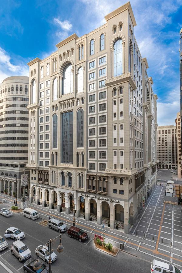 Al Aqeeq Madinah Hotel Медина Экстерьер фото The photo depicts a large, modern building with a distinctive architectural style. The structure shows a blend of classic and contemporary design elements, featuring ornate details, large glass windows, and a prominent central facade. Surrounding the