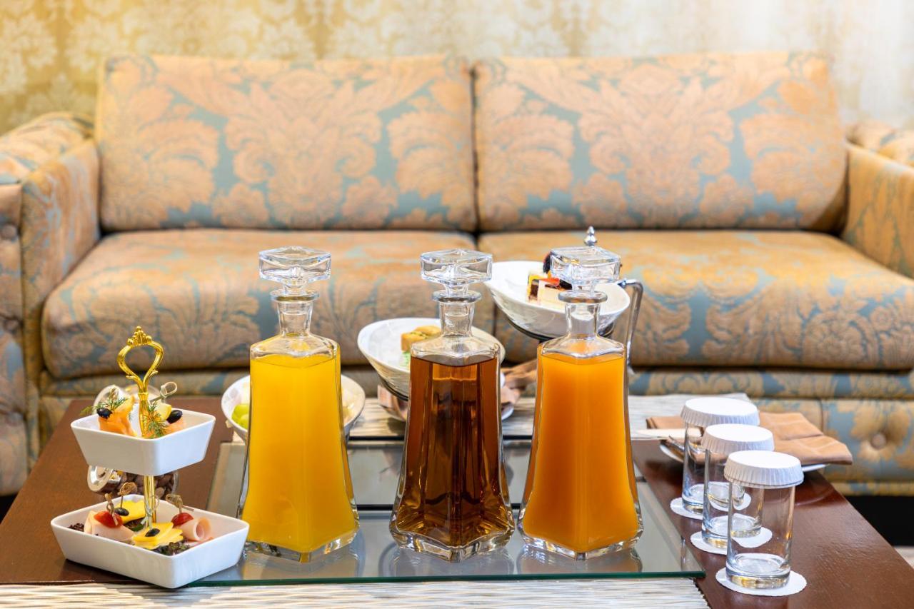 Al Aqeeq Madinah Hotel Медина Экстерьер фото The photo features a beautifully arranged table with several glass decanters filled with liquids. Two decanters, one containing a yellow drink (possibly juice) and another with a darker beverage (possibly tea), are placed prominently. In front of the