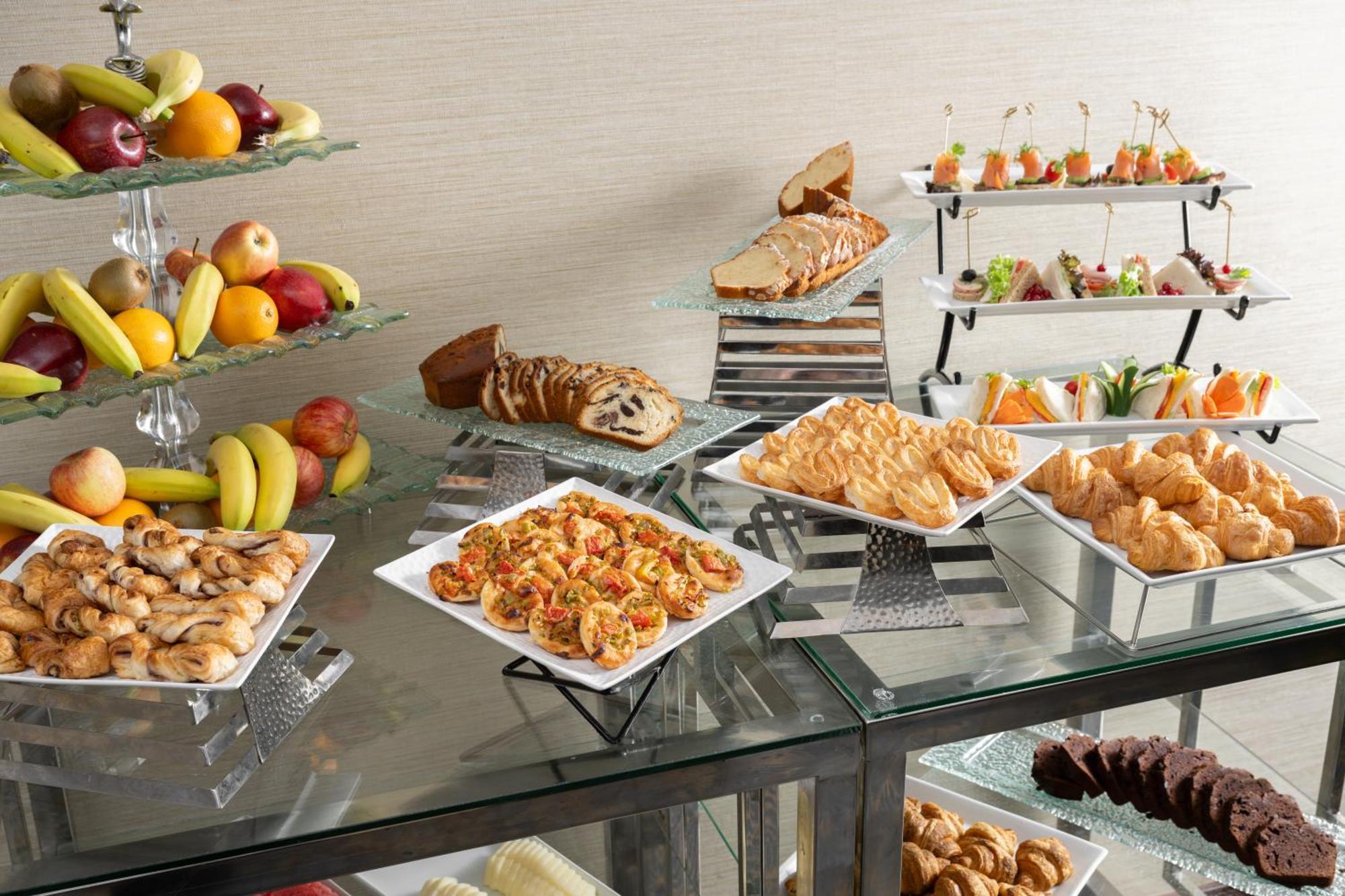 Al Aqeeq Madinah Hotel Медина Экстерьер фото The photo showcases a buffet-style spread featuring a variety of food items. There are several platters with appetizers, including seafood dishes, pastries, and other savory items. In addition, there is a selection of fresh fruit displayed on a glass