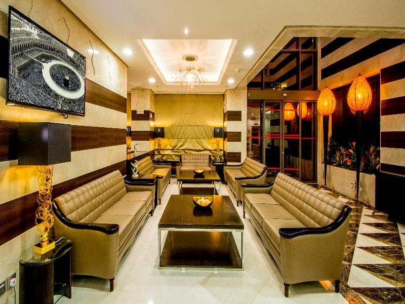 Al Aqeeq Madinah Hotel Медина Экстерьер фото The photo shows a modern and stylish living area or lounge. It features several beige leather sofas arranged around a central black coffee table. The walls are decorated with a mix of light colors and dark wooden accents. There is a large flat-screen