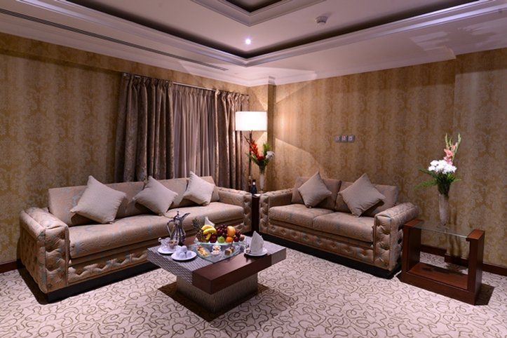 Al Aqeeq Madinah Hotel Медина Экстерьер фото The photo depicts a well-decorated living room. It features two elegant sofas with decorative pillows, positioned across from each other. A coffee table is centered between them, adorned with a variety of fruits and possibly some snacks or beverages.