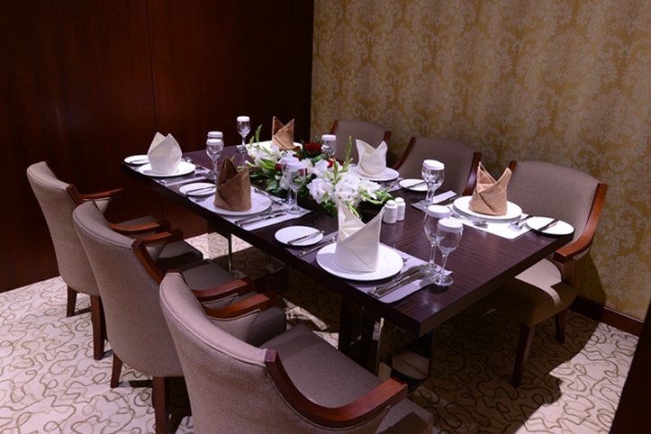 Al Aqeeq Madinah Hotel Медина Экстерьер фото The photo shows an elegantly arranged dining table set for a formal meal. The table is rectangular and made of dark wood. It is adorned with white plates, glassware, and neatly folded napkins placed on top of each plate. The napkins are in two colors